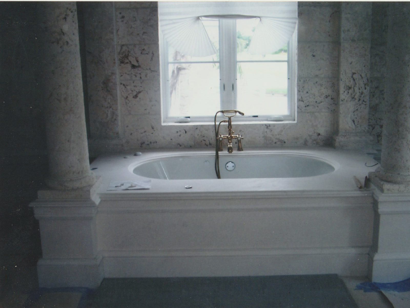 Coral stone bathroom with custom marble tub and brass fixtures by Luis's Home Repairs